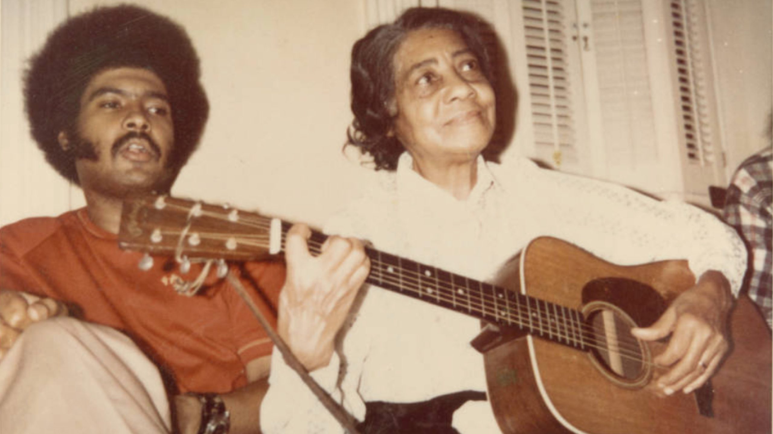 Elizabeth Cotten holding her guitar, Sparky Rucker on the left. Photo from Mike Seeger Collection