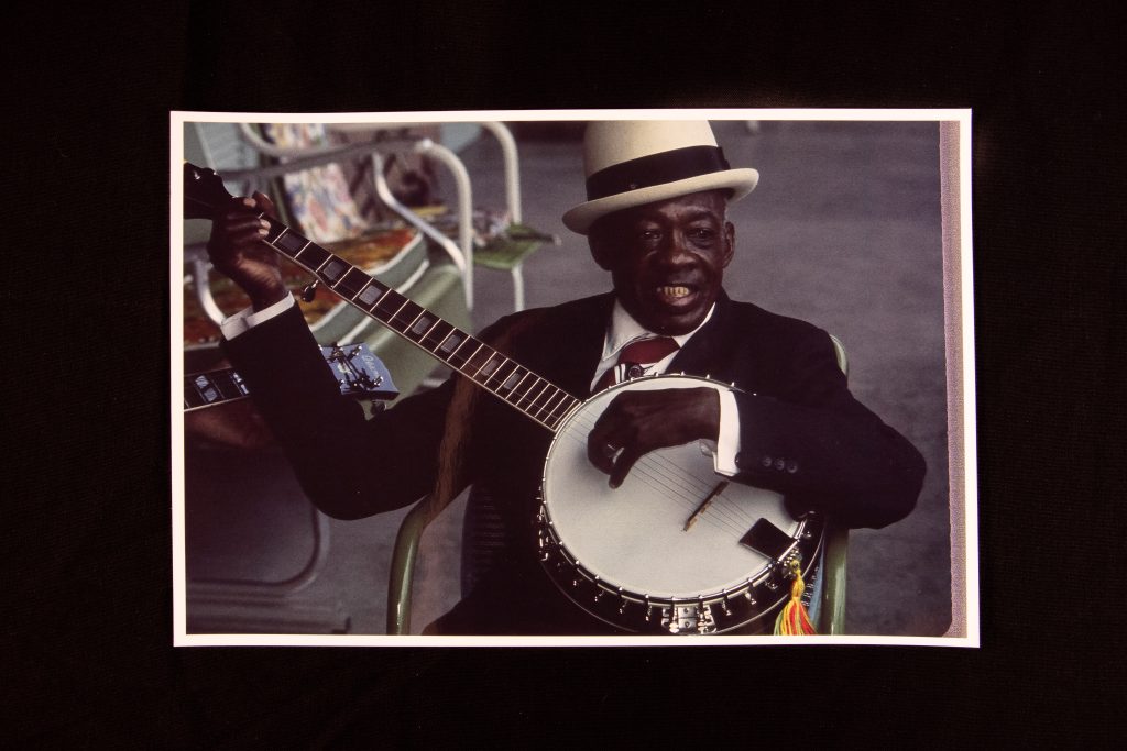 Color photo print of a middle aged black man playing a banjo.