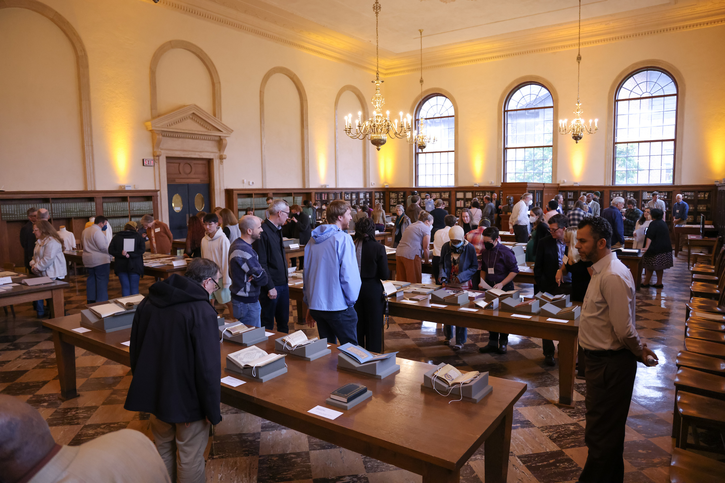 A crowd of people walk around the Fearrington Reading Room in Wilson Library during Recent Acquisitions Evening event.